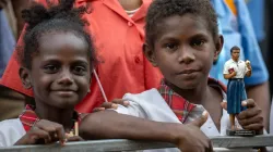 Two children, one of them holding a statue of Blessed Peter To Rot, await the visit of Pope Francis at the Caritas Technical Secondary School in Port Moresby, Papua New Guinea, Sept. 7, 2024 / Credit: Daniel Ibáñez/CNA