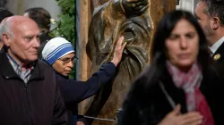 A Sister of the Missionaries of Charity touches the bronze Holy Door at the papal basilica during its opening for the 2025 Jubilee Year. The religious sister, wearing the distinctive white and blue habit of the order founded by Mother Teresa, joins other faithful in this traditional gesture of devotion as they pass through the ceremonial door on Jan. 1, 2025. / Credit: Daniel Ibáñez/CNA