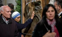 A Sister of the Missionaries of Charity touches the bronze Holy Door at the papal basilica during its opening for the 2025 Jubilee Year. The religious sister, wearing the distinctive white and blue habit of the order founded by Mother Teresa, joins other faithful in this traditional gesture of devotion as they pass through the ceremonial door on Jan. 1, 2025. / Credit: Daniel Ibáñez/CNA