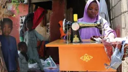 Fatima sewing clothes for a customer in her home, surrounded by her children. Credit: Jesuits Refugee Service (JRS)