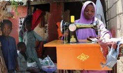 Fatima sewing clothes for a customer in her home, surrounded by her children. Credit: Jesuits Refugee Service (JRS)