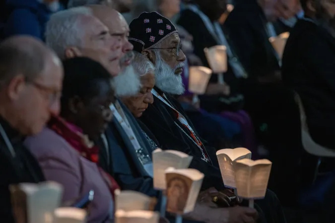 Participants hold candles as they pray during an ecumenical prayer service on Oct. 11, 2024, in Protomartyrs Square at the Vatican.