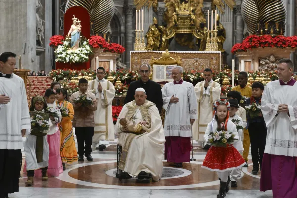 Pope Francis carries the statue of the Child Jesus to place in the Nativity scene inside St. Peter's Basilica at the end of Mass on Christmas Eve, Dec. 24, 2024, surrounded by children dressed in traditional clothing from their countries. / Credit: Vatican Media