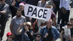 Pilgrims in St. Peter’s Square hold up a sign that says “pace,” which means “peace” in Italian. / Credit: Vatican Media