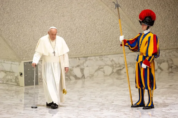 Pope Francis walks with a cane as he enters the Vatican's Pope Paul VI Hall to hold his weekly general audience on Aug. 21, 2024.