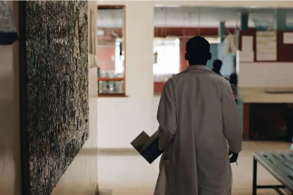 Doctor in white medical gown walking through the hospital lobby in village in Africa. Via Shutterstock