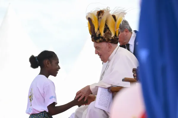 Pope Francis wears a traditional head dress as greets a young girl in Vanimo, Papua New Guinea, Sept. 8, 2024 / Vatican Media