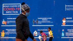 People walk past a COVID-19 advertisement in the township of Soweto outside of Johannesburg, South Africa, July 13, 2020. / AP