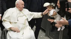 Pope Francis, seated in a wheelchair, greets a child during the pope's general audience at the Vatican on Jan. 25, 2023. | Vatican Media