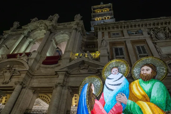 An illuminated nativity scene display stands before the baroque facade of the Basilica of St. Mary Major at night, with the church's iconic bell tower visible against the dark Roman sky, on Jan. 1, 2025.