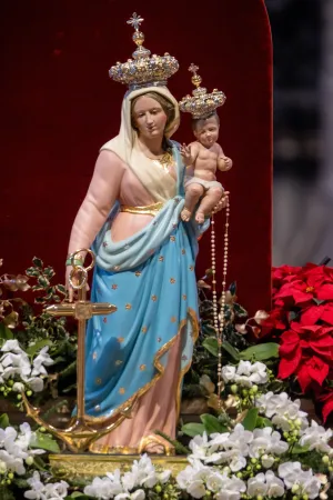 A statue of Mary and the Child Jesus, adorned with crowns and surrounded by poinsettias and white orchids, is displayed during the New Year's Day Mass at St. Peter's Basilica.