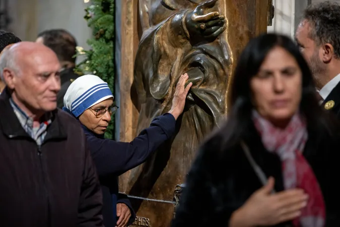 A Sister of the Missionaries of Charity touches the bronze Holy Door at the papal basilica during its opening for the 2025 Jubilee Year. The religious sister, wearing the distinctive white and blue habit of the order founded by Mother Teresa, joins other faithful in this traditional gesture of devotion as they pass through the ceremonial door on Jan. 1, 2025.