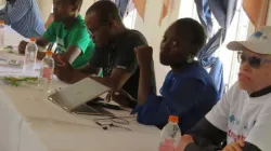 Masapi (in white t-shirt) and others following the proceedings of the meeting. Credit: Courtesy photo