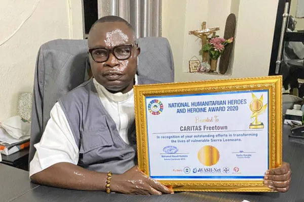 Fr. Peter Konteh with the award received by Caritas Freetown during the commemoration of the World Humanitarian Day on August 19. / Caritas Freetown