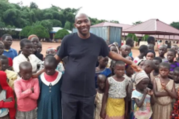 Pastor Solomon Folorunsho, Coordinator of Home for the Needy in Nigeria’s Benin State poses with a section of displaced children at the camp. Credit: Denis Hurley Peace Institue