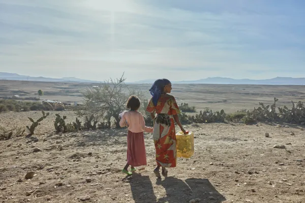 A woman and a girl in Tigray walk with supplies. The founder and CEO of the global school-feeding charity Mary’s Meals visited northern Ethiopia in March and confirmed reports of a widespread hunger crisis unfolding rapidly in Tigray in the aftermath of a two-year civil war and ongoing drought.  / Credit: Armstrong Studios/2024