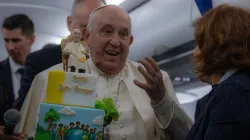 Pope Francis is presented with a birthday cake aboard the papal plane on the return from his trip to Corsica on Sunday, Dec. 15, 2024. / Credit: Daniel Ibáñez/CNA