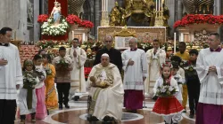 Pope Francis carries the statue of the Child Jesus to place in the Nativity scene inside St. Peter's Basilica at the end of Mass on Christmas Eve, Dec. 24, 2024, surrounded by children dressed in traditional clothing from their countries. / Credit: Vatican Media