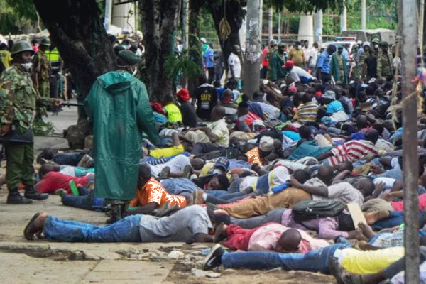 Police force ferry passengers to lie down after firing tear gas and detaining them in Mombasa, Kenya. / AFP